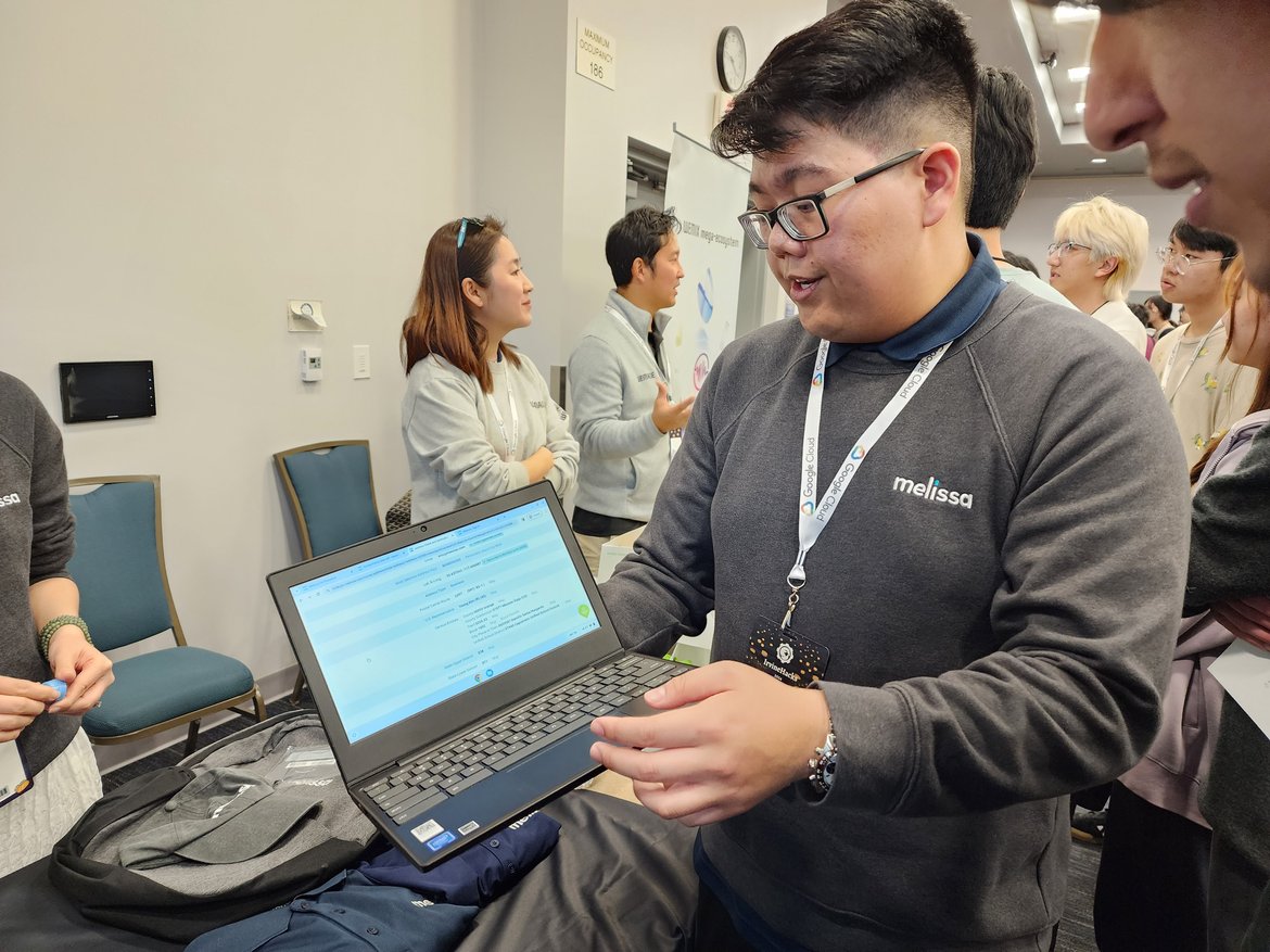 Melissa staff explains use cases for Melissa's API to attendees, on his laptop.