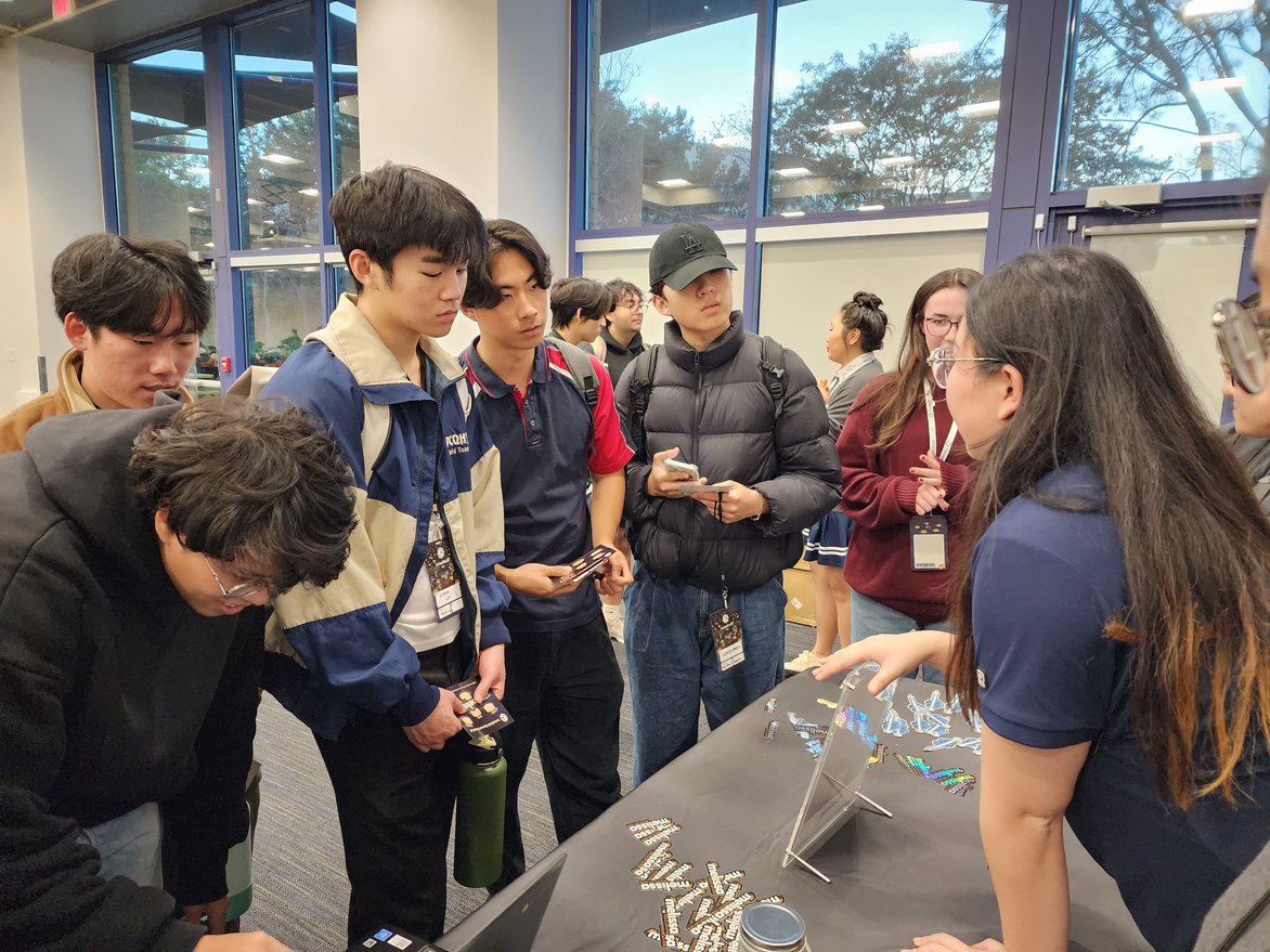 Melissa table staff explains Melissa API tools to hackathon attendees. 